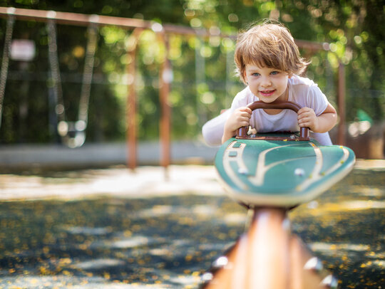 Bild: Kind auf einer Wippe auf dem Spielplatz