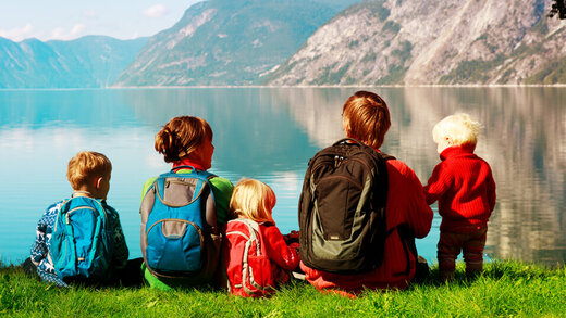 Familie mit drei kleinen Kindern sitzt in den Bergen an einem See