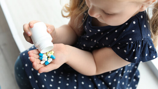 Ein kleines Mädchen findet Medikamente und schüttet sie in ihre Hand