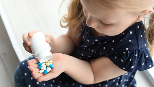 Ein kleines Mädchen schüttet sich Medikamente in die Hand
