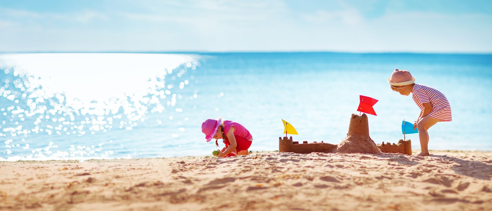 Zwei Kindern bauen eine Sandburg am Strand