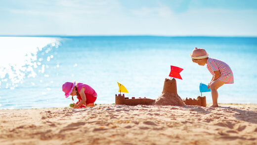 Zwei kleine Kinder bauen eine Sandburg am Strand