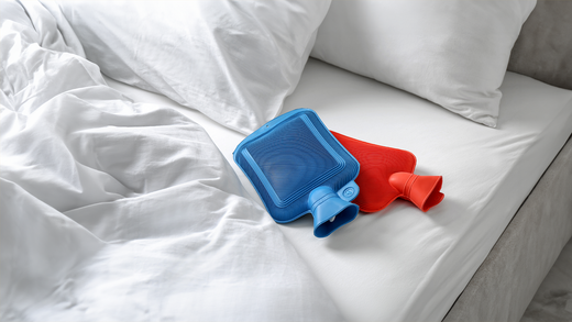 Zwei bunte Wärmflaschen liegen im Bett. 