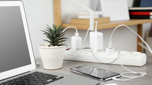 Mehrfachstecker mit verschiedenen angeschlossen Geräten auf dem Schreibtisch in einem Home Office. 