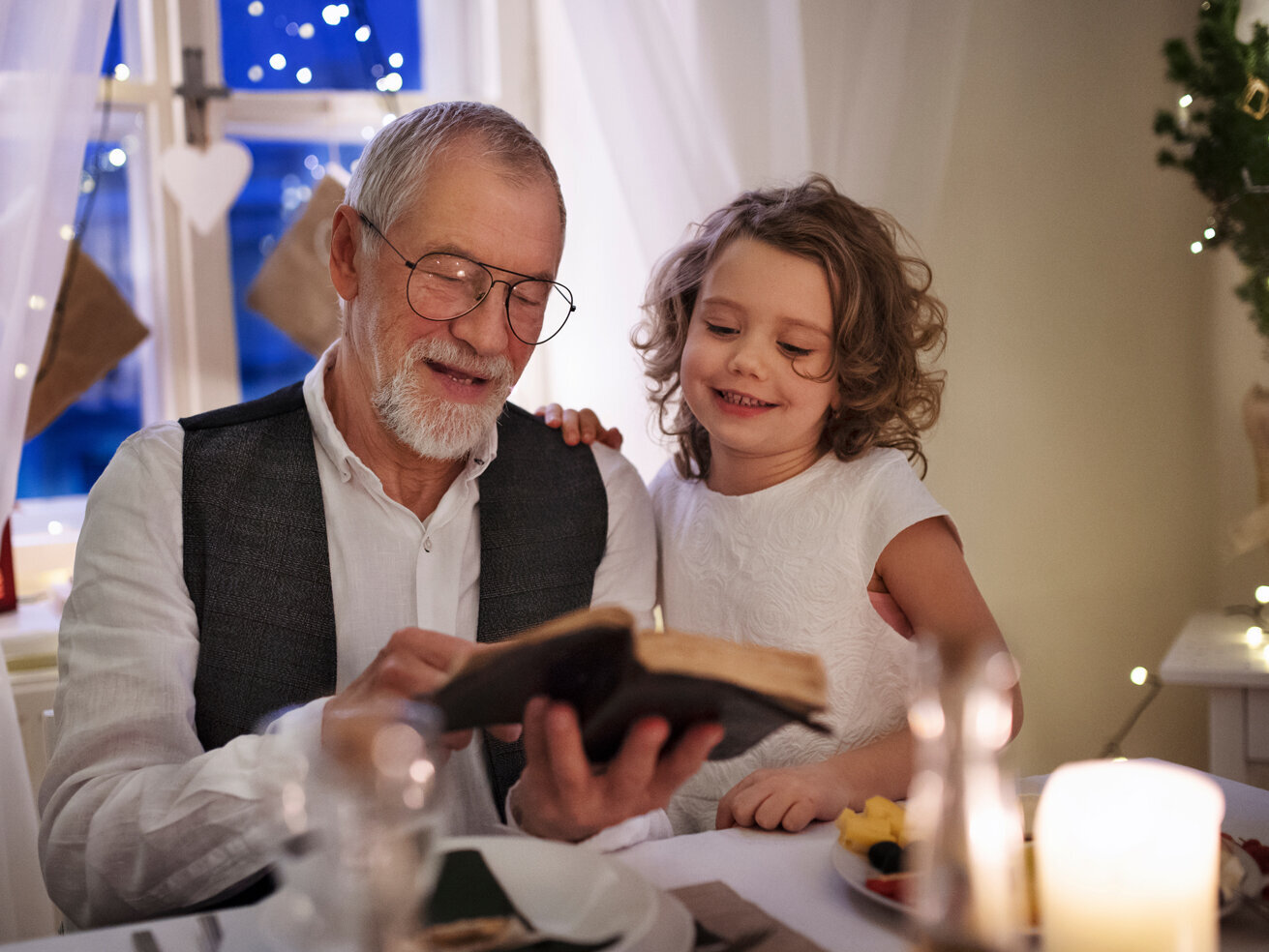 Großvater liest Enkelin an Weihnachten etwas vor.