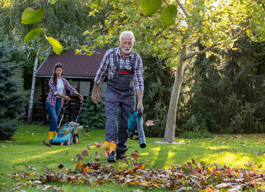 Senioren arbeitet mit einem Laubbläser im Garten