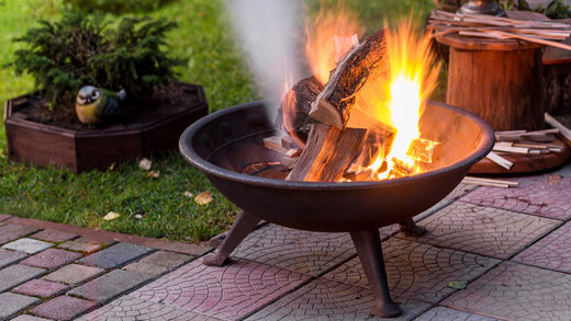 Eine Feuerschale in einem Garten, in dem ein kleines Feuer brennt.