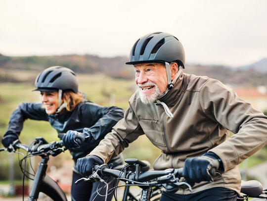 Senioren fahren Ebike und tragen dabei Helme