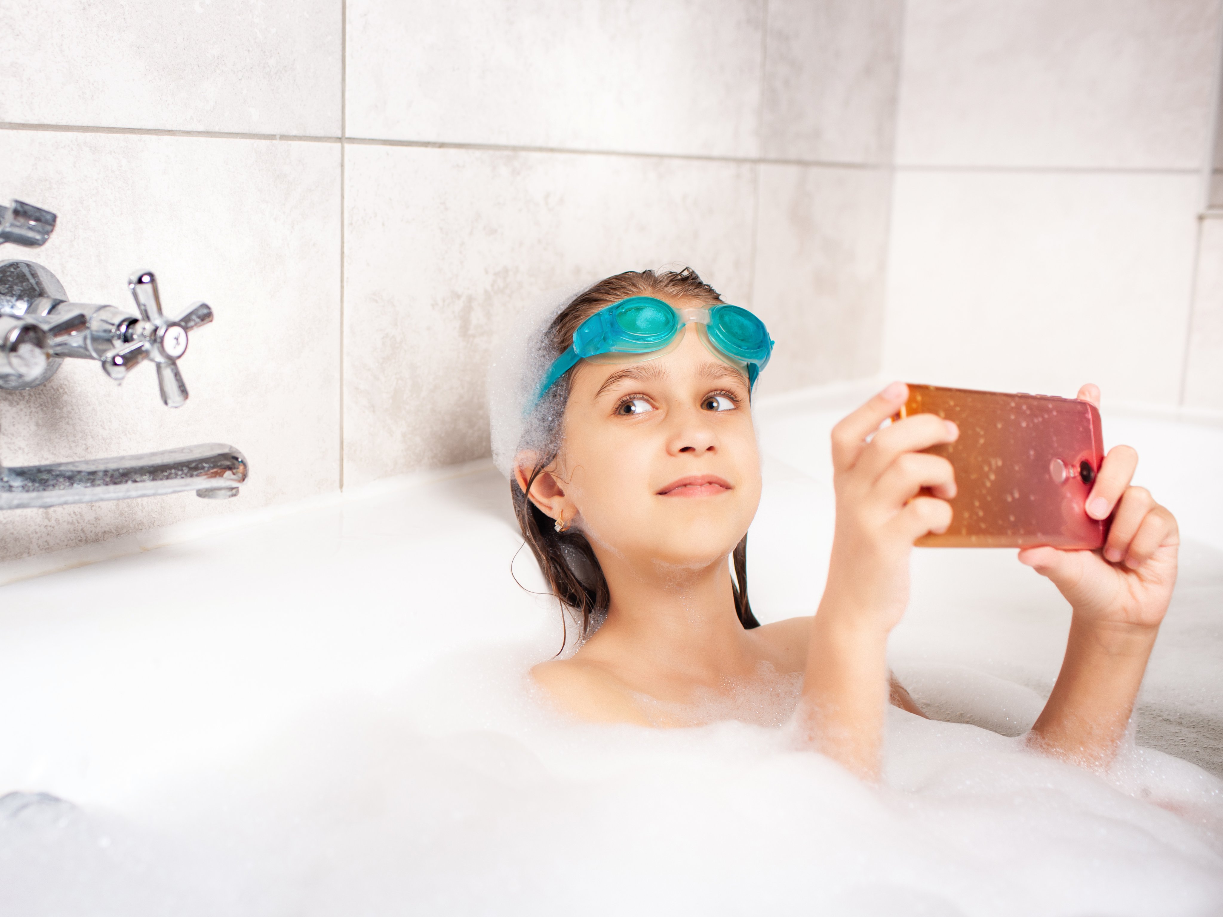 Bild: Kind spielt in der Badewanne am Handy