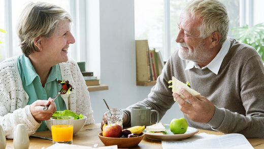 Ein älteres Ehepaar sitzt am Tisch am Tisch und isst ein gesundes Frühstück