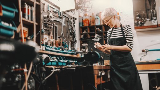 Eine Frau arbeitet in ihrer Hobbywerkstatt. Die Geräte und Utensilien sind aufgeräumt in Regalen verstaut. 