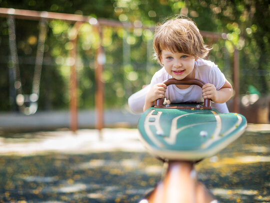 Bild: Kind auf einer Wippe auf dem Spielplatz