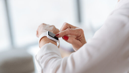 Eine Person betätigt ihre Smartphone am Handgelenk. Zu sehen sind nur die Arme. 