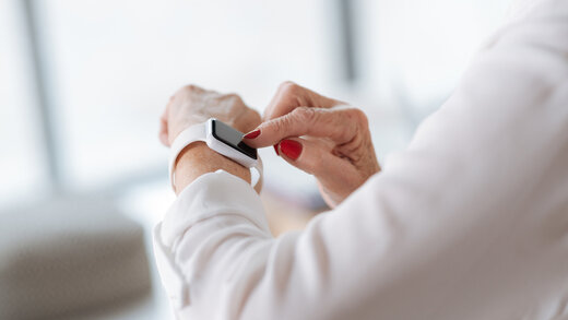 Eine Person betätigt ihre Smartphone am Handgelenk. Zu sehen sind nur die Arme. 