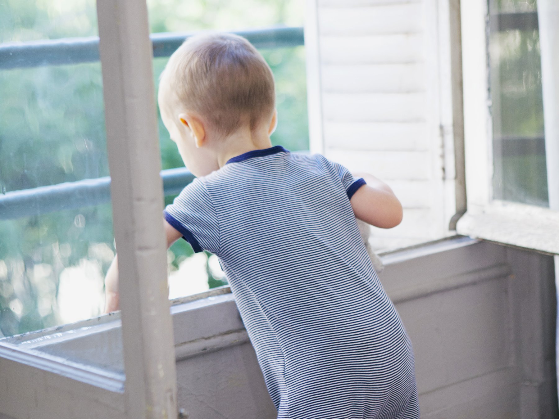 Kleinkind lehnt sich aus einem offenem Fenster