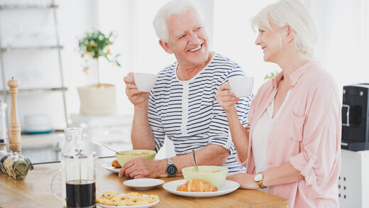 Ein älterer Mann und eine ältere Damen sitzen zusammen am Tisch und essen