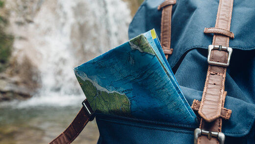 Eine Landkarte guckt aus einem Rucksack heraus.