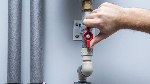Person dreht den Gashahn an einer Gasleitung ab. Dies zeigt eine Sicherheitsmaßnahme, um potenzielle Gaslecks zu verhindern und die Gefahr einer Explosion oder eines Brandes zu minimieren.