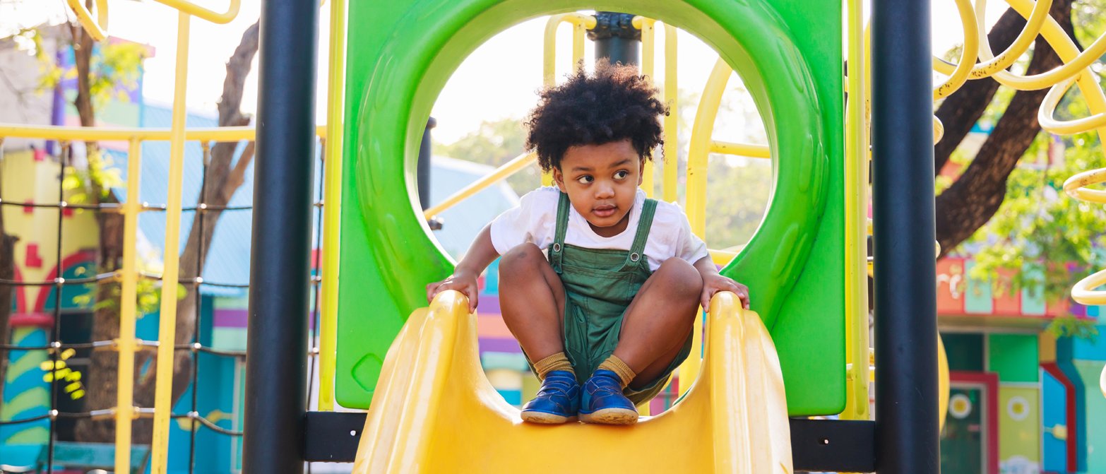 Kleinkind auf einer Rutsche auf dem Spielplatz