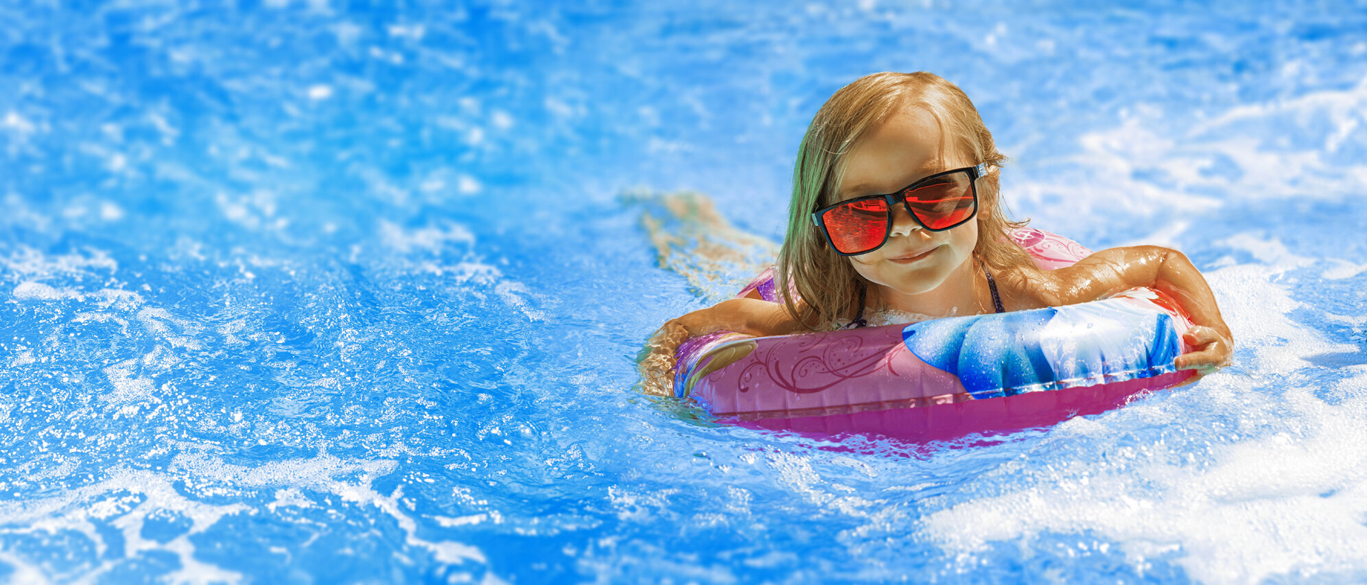 Kind mit einer Sonnenbrille im Pool
