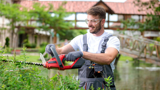 Ein Mann arbeiten im Garten mit einer Heckenschere