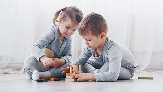 Ein kleiner Junge und ein kleines Mädchen spielen mit Bauklötzen im Kinderzimmer