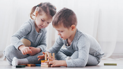 Zwei kleine Kinder spielen mit bunten Bauklötzen