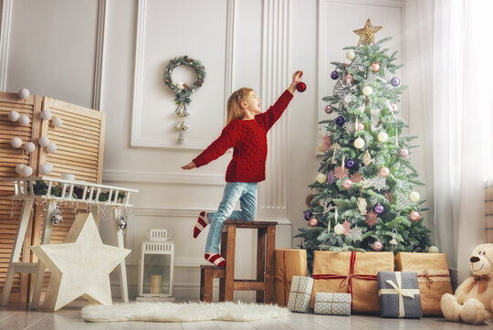 Kind schmückt den Weihnachtsbaum mit einer Christbaumkugel